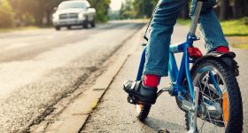 A boy on bike and a car on the road